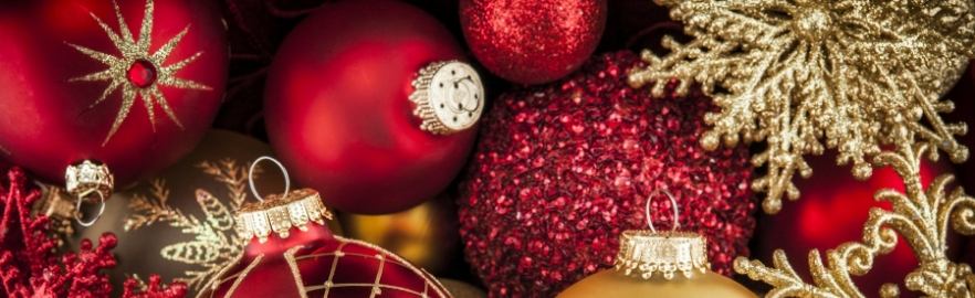 Zbliżenie na bogatą kolekcję czerwonych i złotych ozdób świątecznych, w tym błyszczące bombki i złote śnieżynki.
